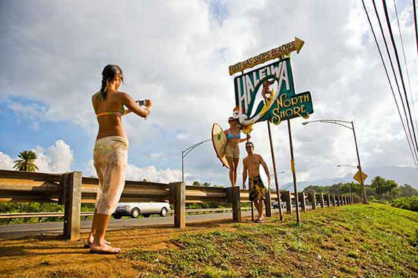 Woman taking photograph at Oahu's North Shore sign